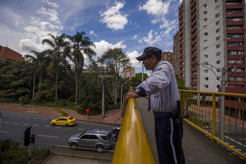Trabajador de aseo con uniforme y herramientas en un centro comercial vacío tras recortes por alza del salario mínimo en Colombia