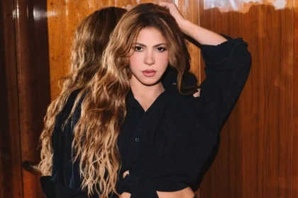 Shakira en concierto con micrófono, celebrando su nominación histórica al Salón de la Fama del Rock & Roll, rodeada de luces escénicas