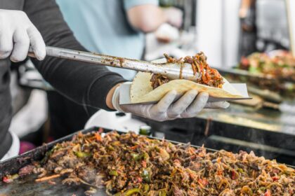Camión de tacos mexicanos en Tokio con comal bola tradicional, sirviendo suadero y carnitas auténticas bajo el cielo urbano