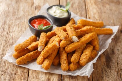 Tiras de pollo doradas con costra de panko crujiente, servidas con salsa agridulce brillante en un plato blanco, listas para el Super Bowl