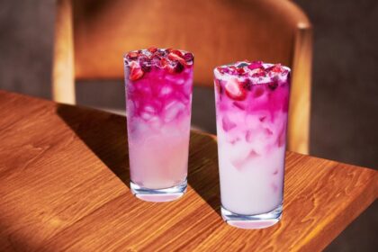 Vaso de Pink Cannon Ball con degradado rosa de fresa, mango y pitahaya, decorado con trozos de fruta fresca y leche de coco