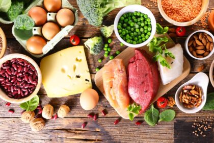 Plato con carne, quesos y vegetales mostrando bacterias resistentes a antibióticos bajo microscopio