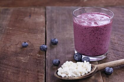 Vaso de kéfir con arándanos y semillas de chía sobre mesa de madera, mezcla probiótica para reparar la microbiota intestinal
