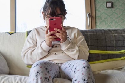 Niño con expresión de ansiedad mirando fijamente una tablet con redes sociales abiertas mientras ignora un balón de fútbol en el suelo