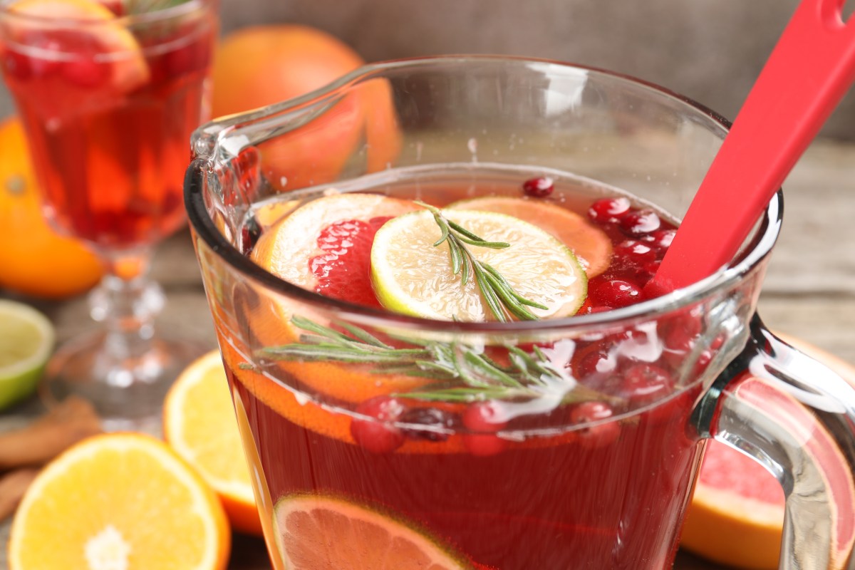 Vaso de Agua de Obispo con su vibrante color rojo de remolacha, rodajas de limón y trozos de fruta fresca flotando