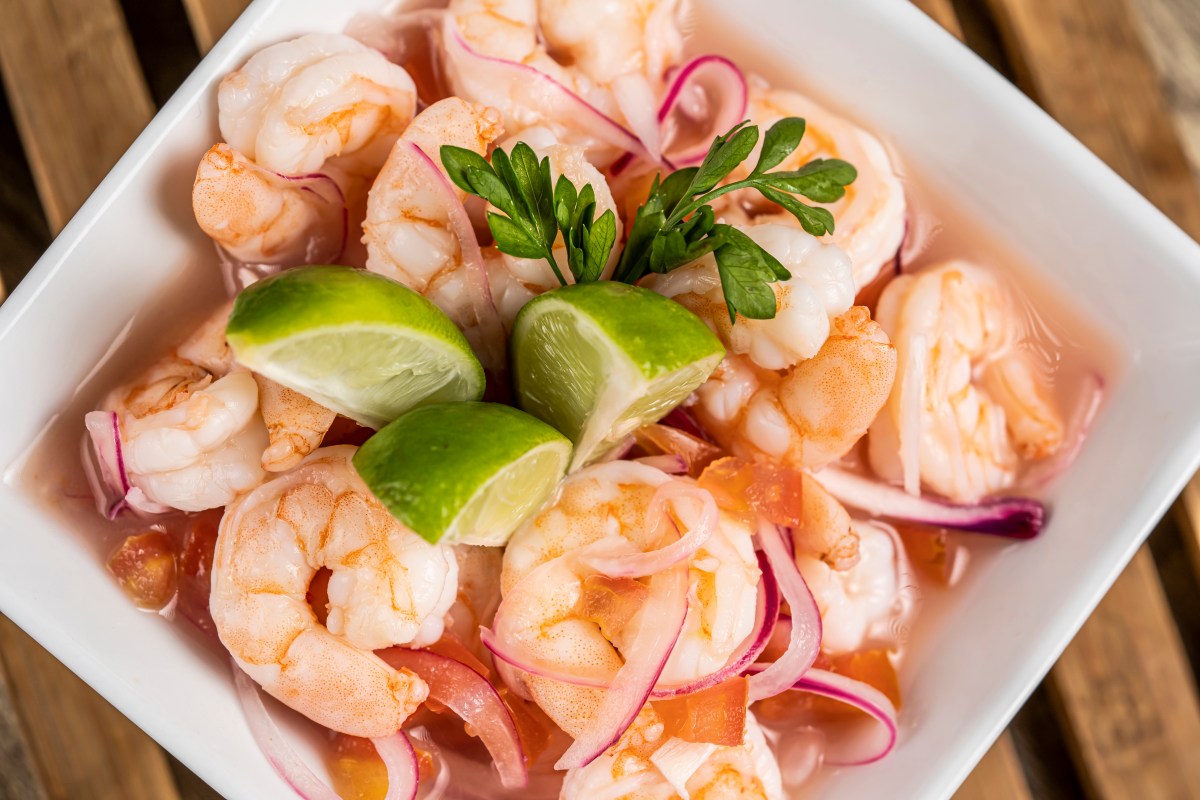 Ceviche de langostinos con leche de tigre ahumada en bowl de cerámica, acompañado de batata y maíz tostado