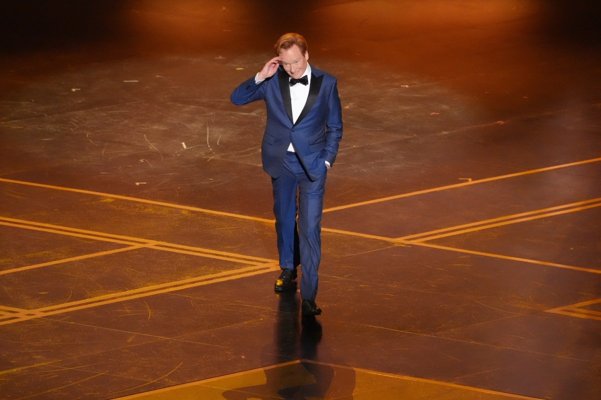 Conan O’Brien en el escenario de los Oscar 2026 con micrófono, tras pronunciar su histórico saludo en español ante el público