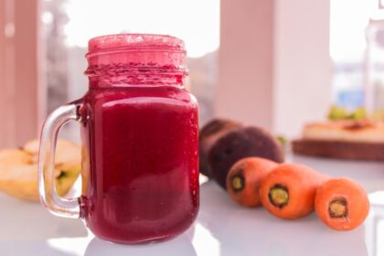 Vaso de jugo de remolacha vibrante con trozos frescos alrededor y fondo de estudio científico sobre presión arterial