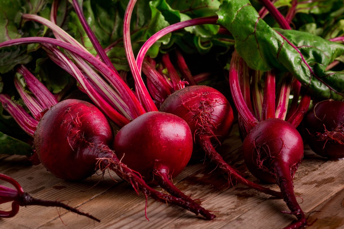 Remolachas púrpuras frescas con hojas verdes brillantes y piel lisa, ideales para ensaladas y jugos nutritivos
