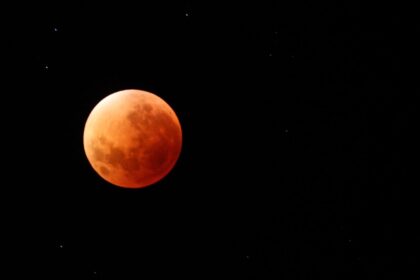 Luna de sangre teñida de rojo cobrizo durante el eclipse lunar 2026 en el cielo de Nueva York, con horizonte urbano al fondo
