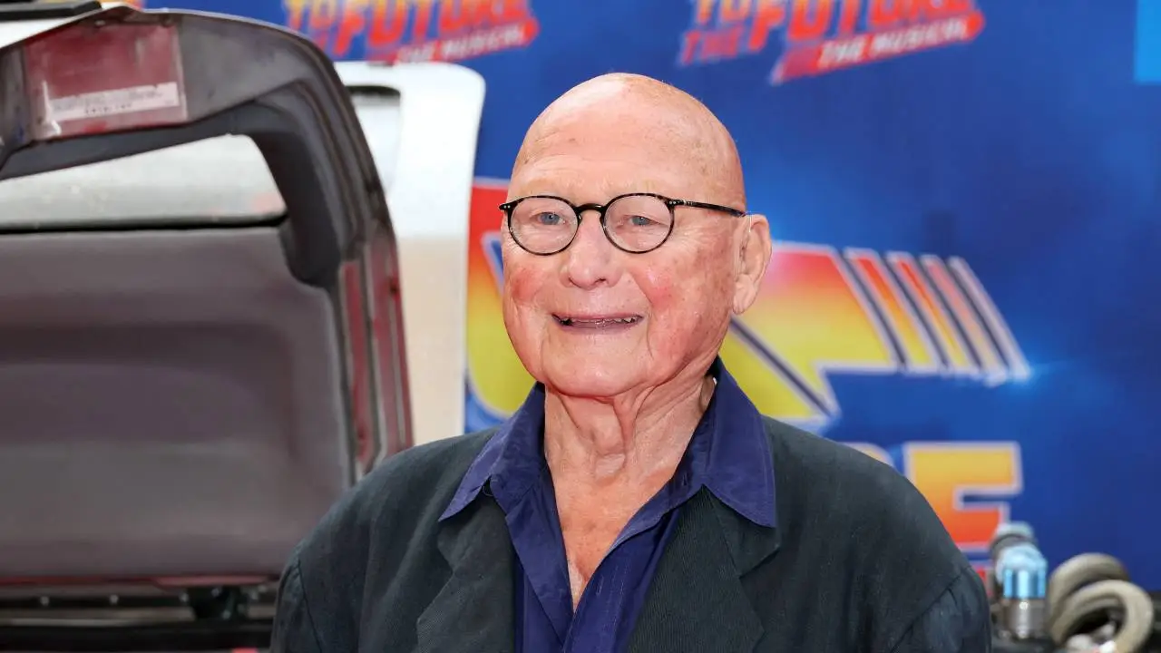 James Tolkan caracterizado como el Sr. Strickland en 'Volver al Futuro', con mirada severa y traje formal en el Instituto Hill Valley