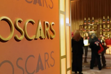 Escenario de los Óscar 2026 con artistas luciendo pins de protesta como 'Artists4Ceasefire' y 'ICE Out' bajo luces doradas
