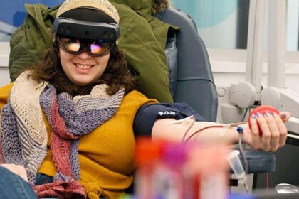 Mujer usando visor de realidad mixta durante donación de sangre, con animación inmersiva de paisaje relajante en pantalla 4K