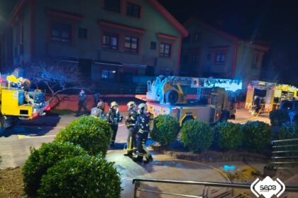 Bomberos con mangueras apagando el incendio en la fachada de un hotel de 3 plantas en Arriondas