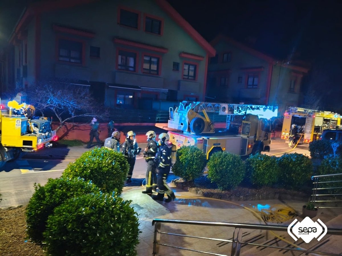 Bomberos con mangueras apagando el incendio en la fachada de un hotel de 3 plantas en Arriondas