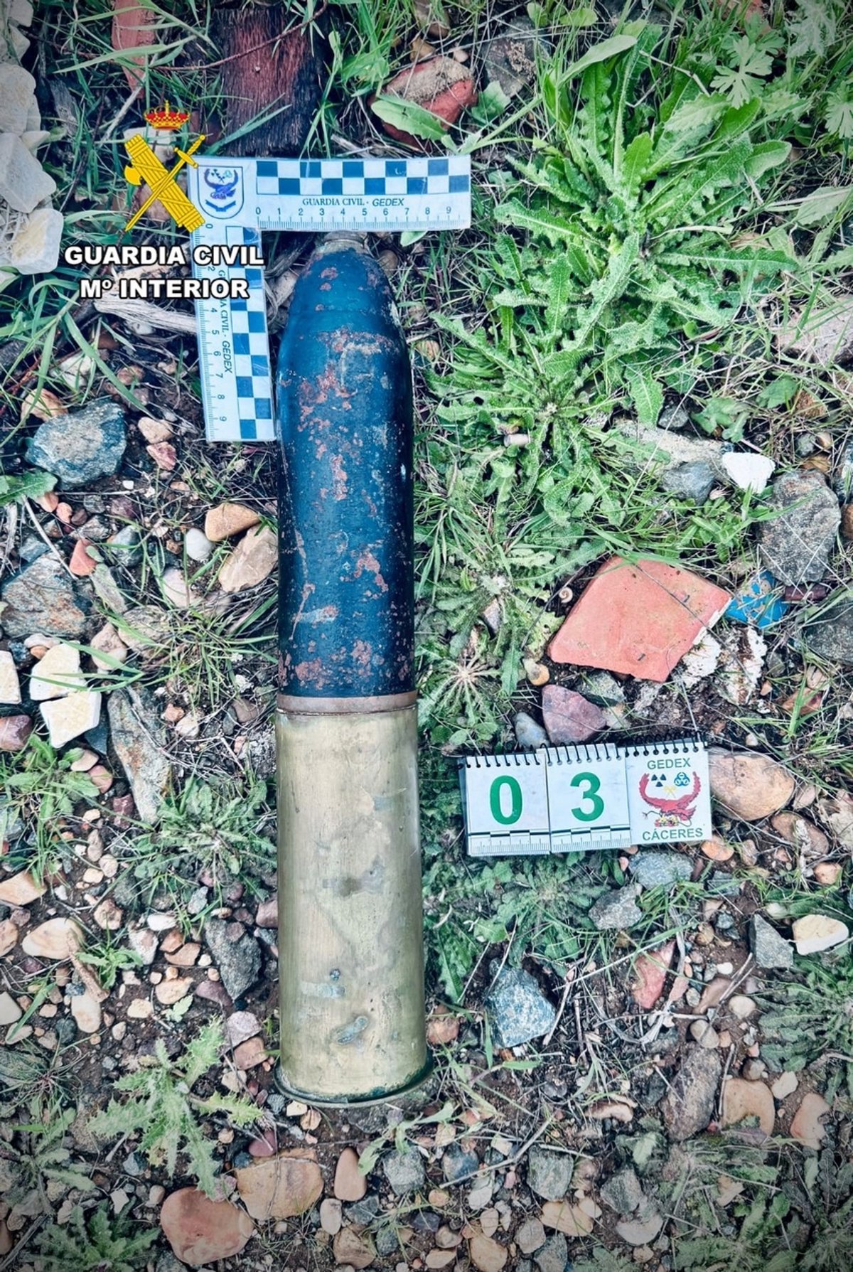 Proyectil de artillería de 65 mm de la Guerra Civil encontrado intacto en un sendero rural de Badajoz, con vaina original visible sobre tierra seca