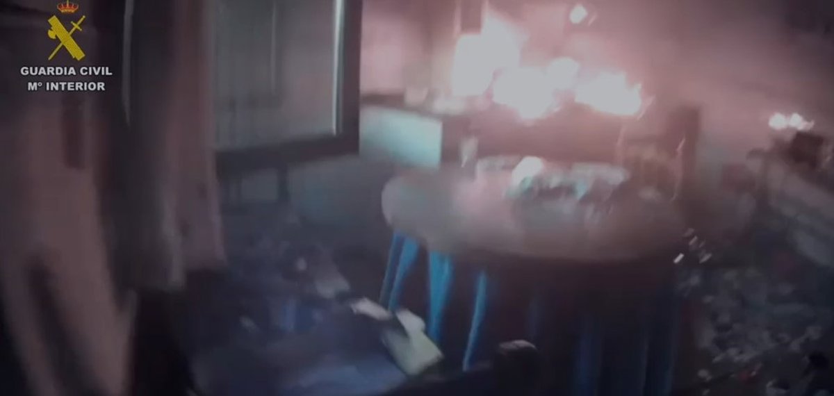 Agentes de la Guardia Civil usando extintor para apagar un incendio en la cocina de una casa rural con humo visible