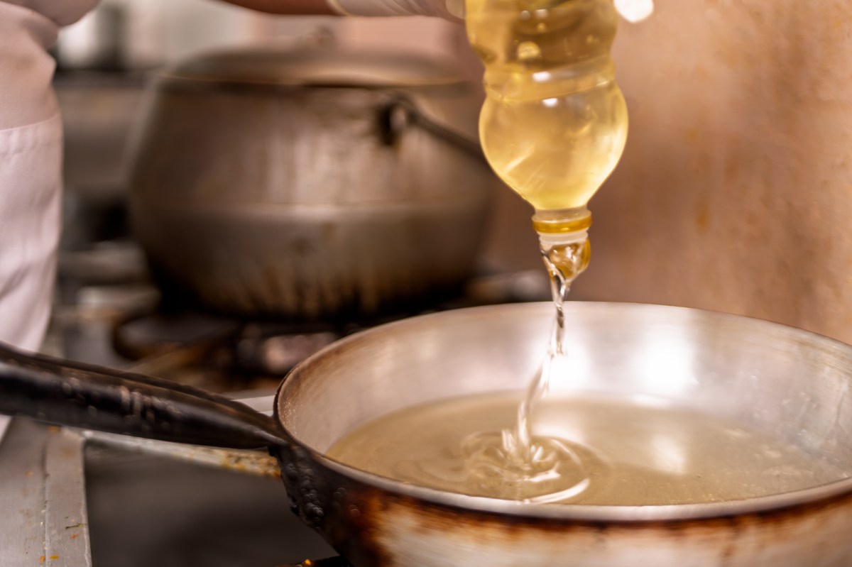 Frasco de aceite de coco con etiqueta de '92% grasa saturada' junto a un electrocardiograma con ritmo cardíaco irregular