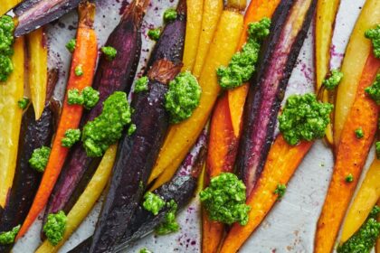 Zanahorias multicolor asadas al horno con bordes caramelizados y pesto verde fresco, lista para servir en mesa pascual