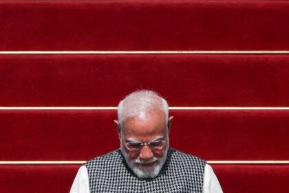 Gráfico de la rupia india en caída libre frente al dólar con datos de 2026 y foto de billetes de 100 rupias