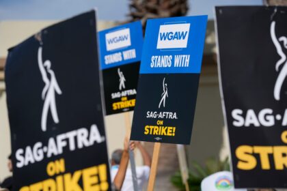 Firma simbólica del acuerdo WGA 2024 entre representantes de guionistas y estudios con documentos y apretón de manos