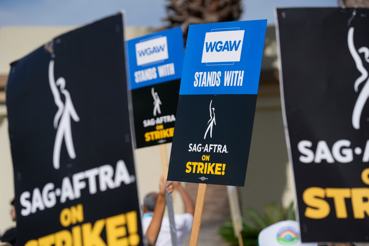 Firma simbólica del acuerdo WGA 2024 entre representantes de guionistas y estudios con documentos y apretón de manos
