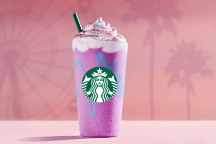 Vaso colorido del Unicorn Frappuccino 2026 con fondo de atardecer en Coachella y detalles de purpurina