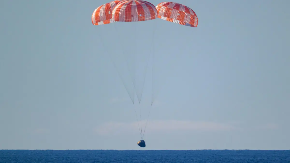 Cápsula Orión de Artemis II amerizando en el Pacífico tras misión lunar, con paracaídas desplegados y equipo de recuperación cerca