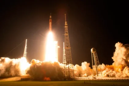 Cohete SLS de la misión Artemis 2 despegando hacia la Luna con la nave Orión en un cielo despejado