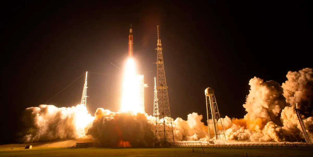 Cohete SLS de la misión Artemis 2 despegando hacia la Luna con la nave Orión en un cielo despejado