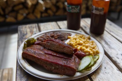 Costillas ahumadas con corteza dorada sobre tabla de roble, típico de la barbacoa EE.UU. con humo de hickory