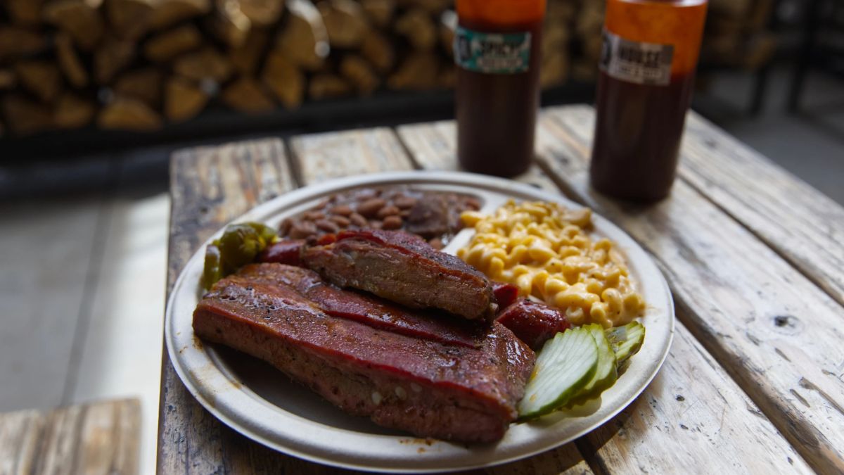 Costillas ahumadas con corteza dorada sobre tabla de roble, típico de la barbacoa EE.UU. con humo de hickory