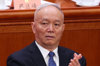 Cai Qi en traje oscuro revisando documentos oficiales junto a guardias, símbolo de su poder tras Xi Jinping en China