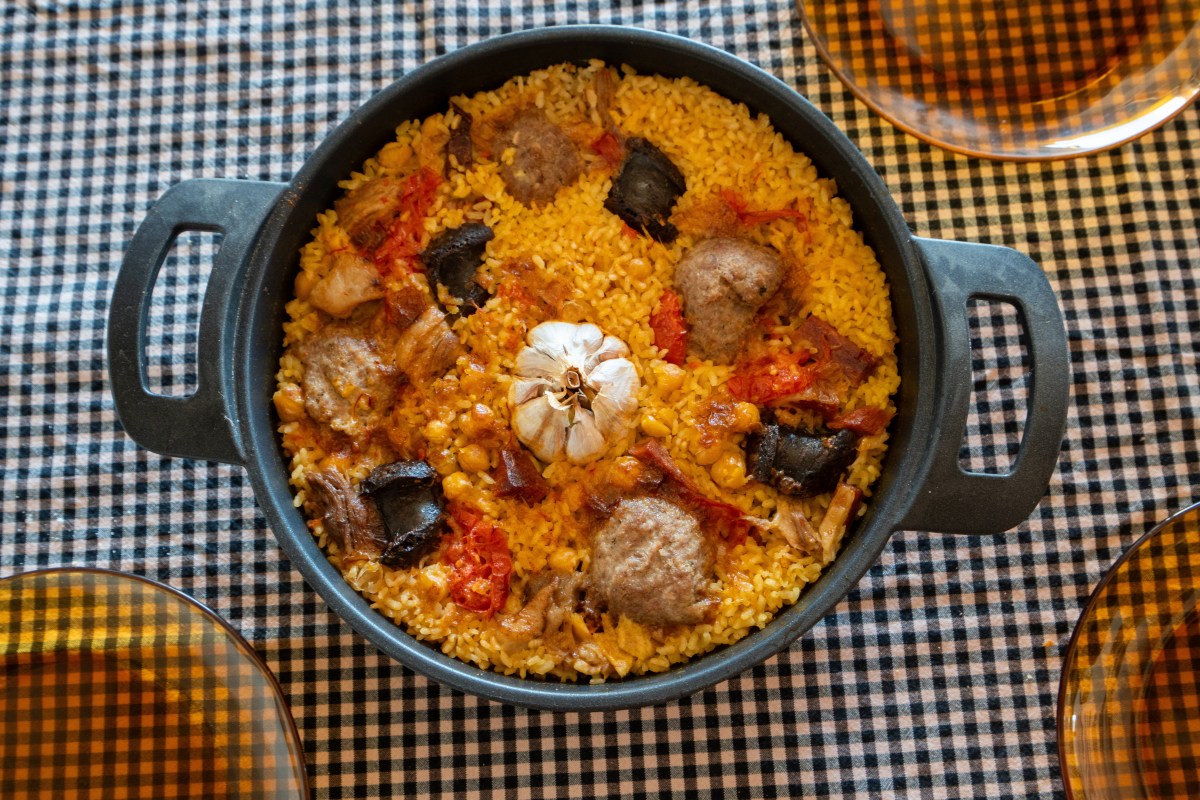 Cazuela de arroz al horno dorado con caldo de cocido, pollo crujiente y verduras confitadas, lista para servir