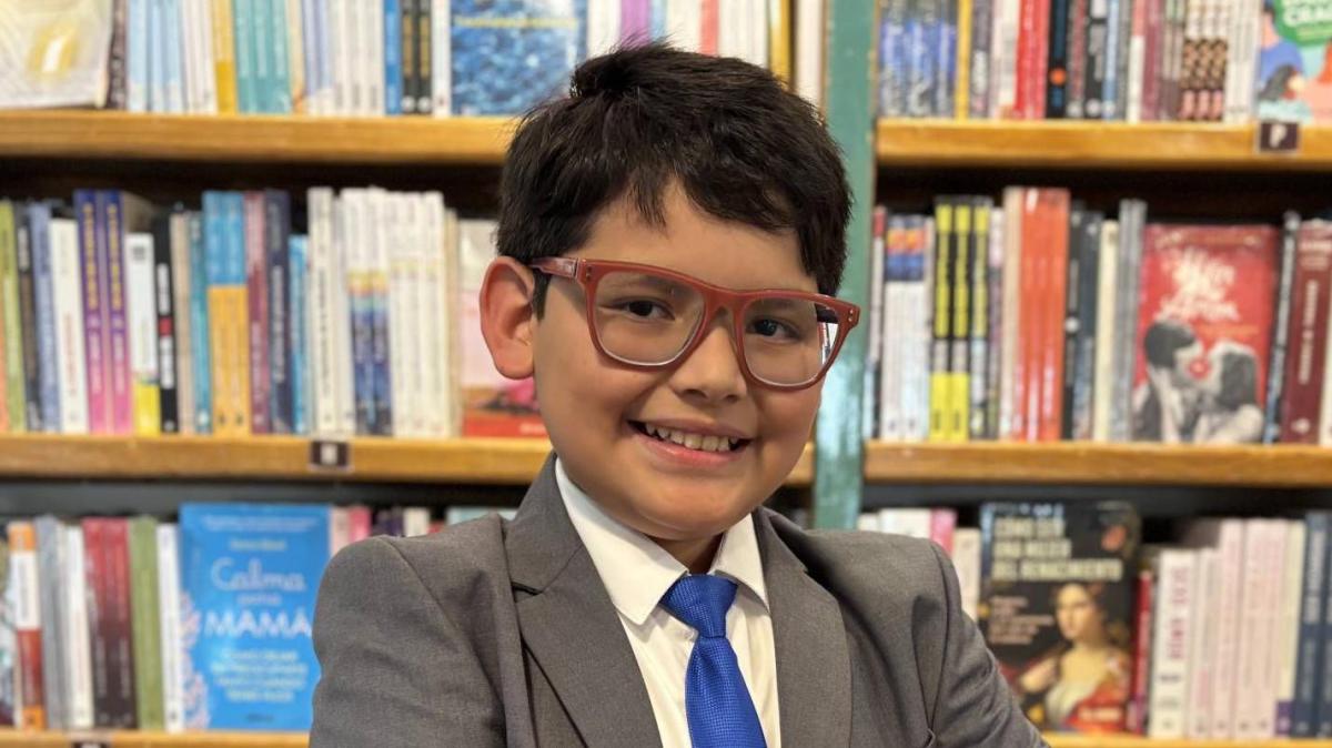 Niño mexicano de 10 años con CI de 162 sonríe frente a un pizarrón con ecuaciones y dibujos de Leonardo da Vinci