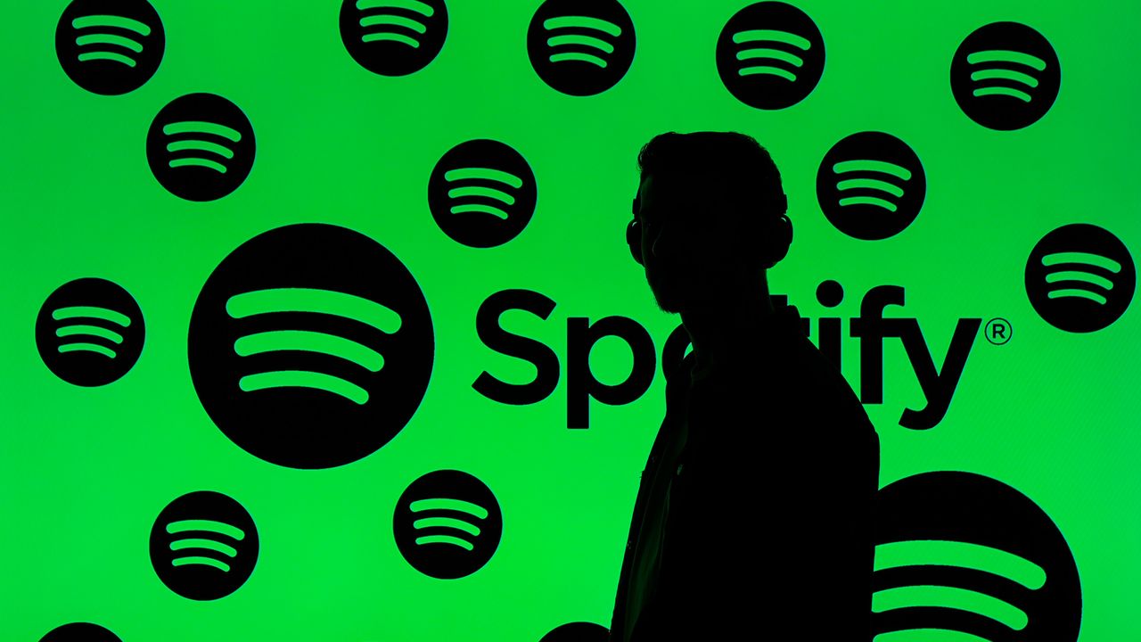 Interfaz de Spotify mostrando un podcast con advertencia de 'contenido verificado' y símbolo de prohibición sobre un altavoz con ondas de voz distorsionadas por IA