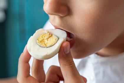 Huevos frescos en un plato blanco con señales visuales de exceso: yemas rotas y gráficos de alerta nutricional