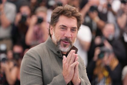 Javier Bardem con micrófono en Cannes 2024 durante discurso sobre 'masculinidad tóxica' y violencia de género, con expresión seria y gesto contundente