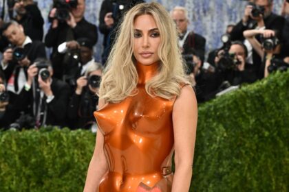 Kim Kardashian revisando apuntes legales con libros de derecho y un portátil, simbolizando su preparación para el 'examen abogacía' pospuesto a 2027