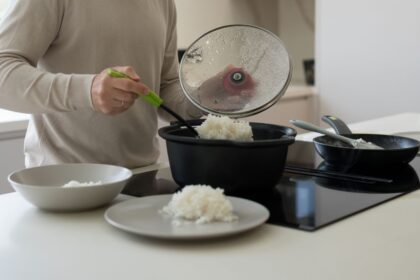 Plato de arroz cocido con termómetro marcando 20°C junto a reloj de arena de 2 horas como recordatorio del límite seguro antes de refrigerar