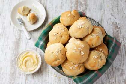 Seis pancitos dorados de avena y mozzarella recién horneados sobre papel vegetal, con textura esponjosa y queso gratinado
