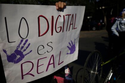 Mano femenina sosteniendo un celular con pantalla rota y la leyenda 'Ley Olimpia: 5 años de impunidad' sobre un fondo de expedientes judiciales apilados
