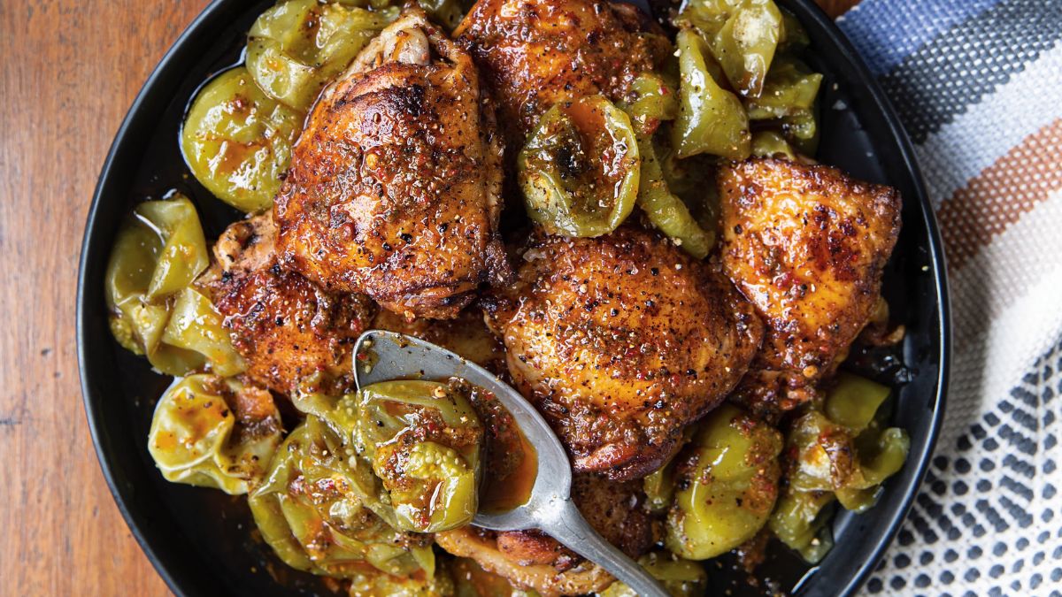 Muslos de pollo dorados con piel crujiente bañados en aderezo rojo de chiles guajillo y tomatillos asados, servidos en molcajete de piedra volcánica