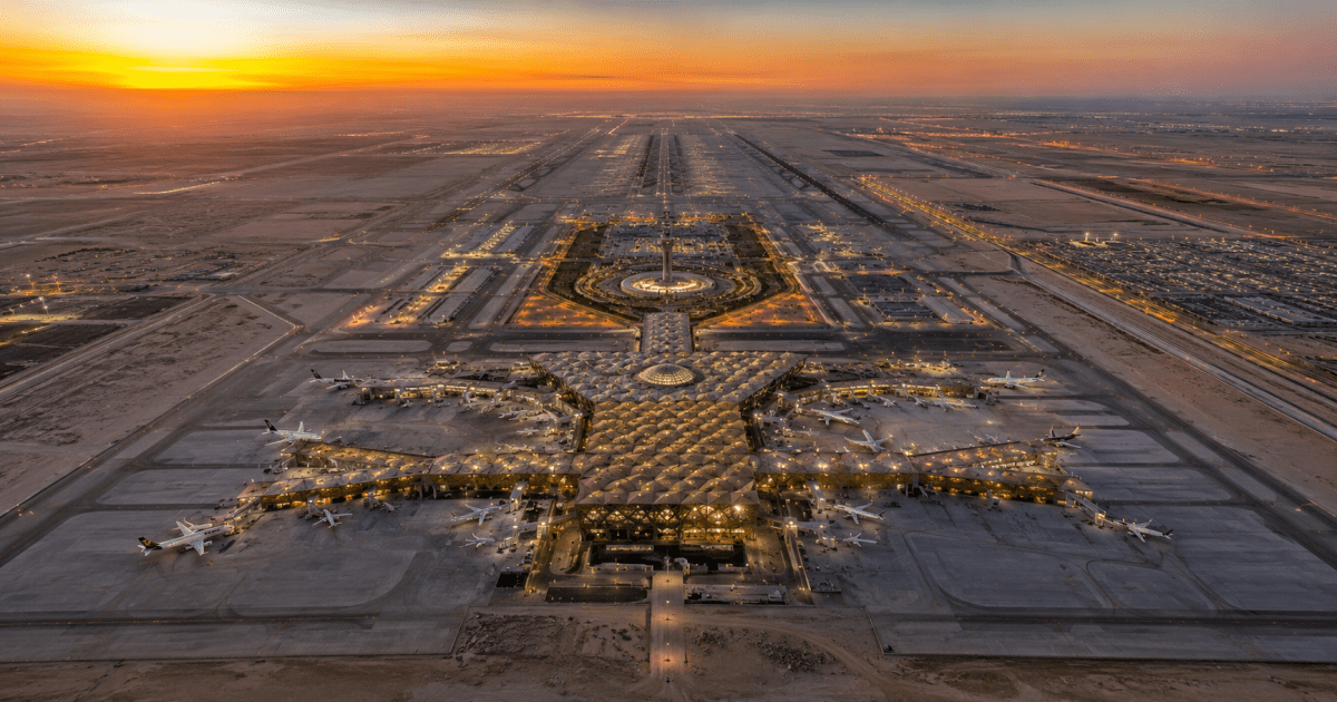 Vista aérea del Aeropuerto Internacional Rey Fahd en Dammam, el más extenso del mundo con 776 km², combinando pistas modernas y zonas de expansión futura bajo el cielo desértico