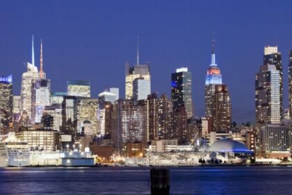 Proyección de 'Top Gun' (1986) en la cubierta del portaaviones USS Intrepid con el skyline de Manhattan iluminado al fondo y aviones históricos alrededor
