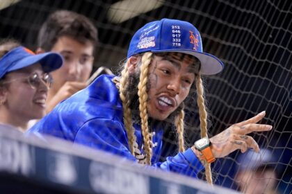 Tekashi 6ix9ine con expresión de alivio al descubrir que su bebé será niño en evento con pantalla azul brillante