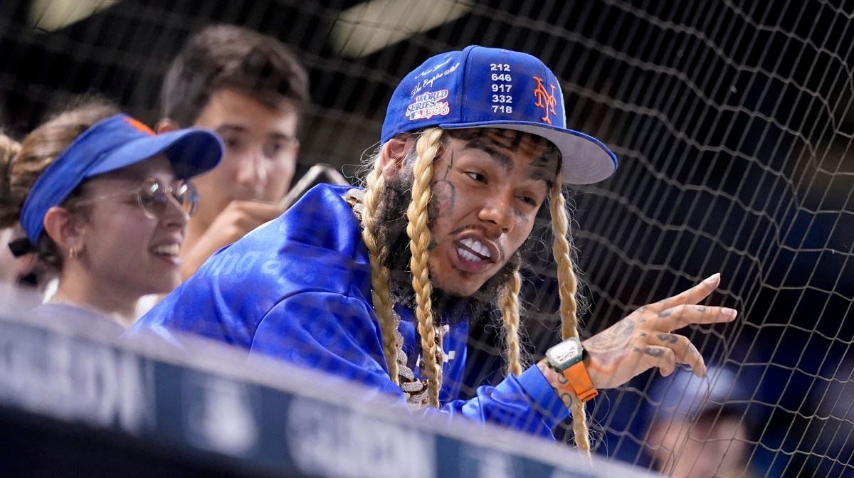Tekashi 6ix9ine con expresión de alivio al descubrir que su bebé será niño en evento con pantalla azul brillante