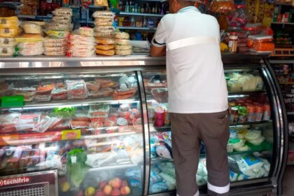 Tendero colombiano revisa inventario reducido en su tienda de barrio mientras ajusta rejas por inseguridad en 2026