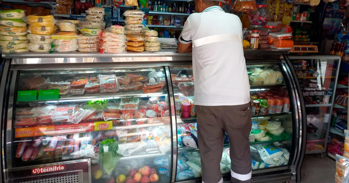 Tendero colombiano revisa inventario reducido en su tienda de barrio mientras ajusta rejas por inseguridad en 2026
