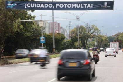 Conductor revisando en su computador la lista de fotomultas anuladas por MinTransporte con comprobante de pago en mano